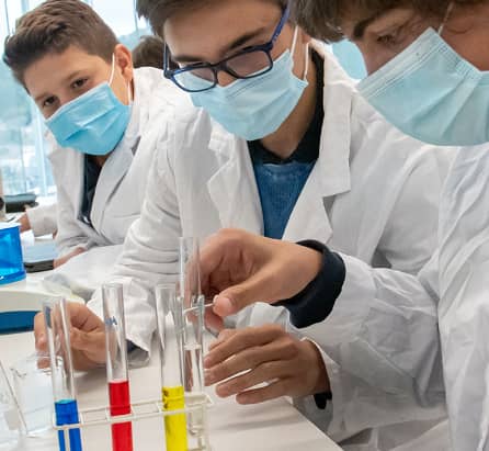 Tres alumnos del área de ciencia y tecnología, analizando líquidos de colores con probetas