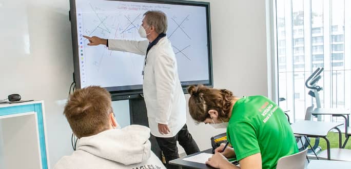The teacher explains to his students using a touch screen
