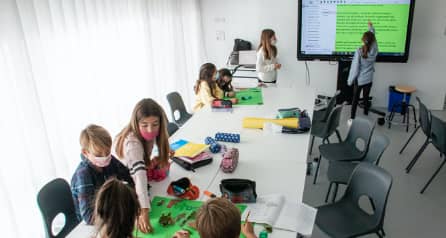 Niños y niñas en un aula interactuando con la pantalla
