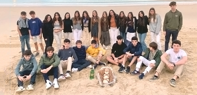 Grupo de alumnos en la playa con la figura de bebe de Jesús en un capazo