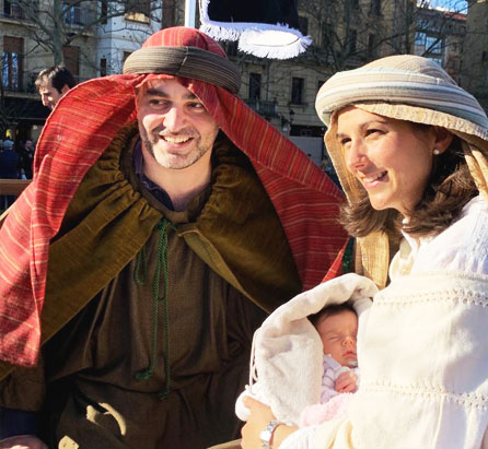 Dos padres vestidos de José y María con un bebe en brazos